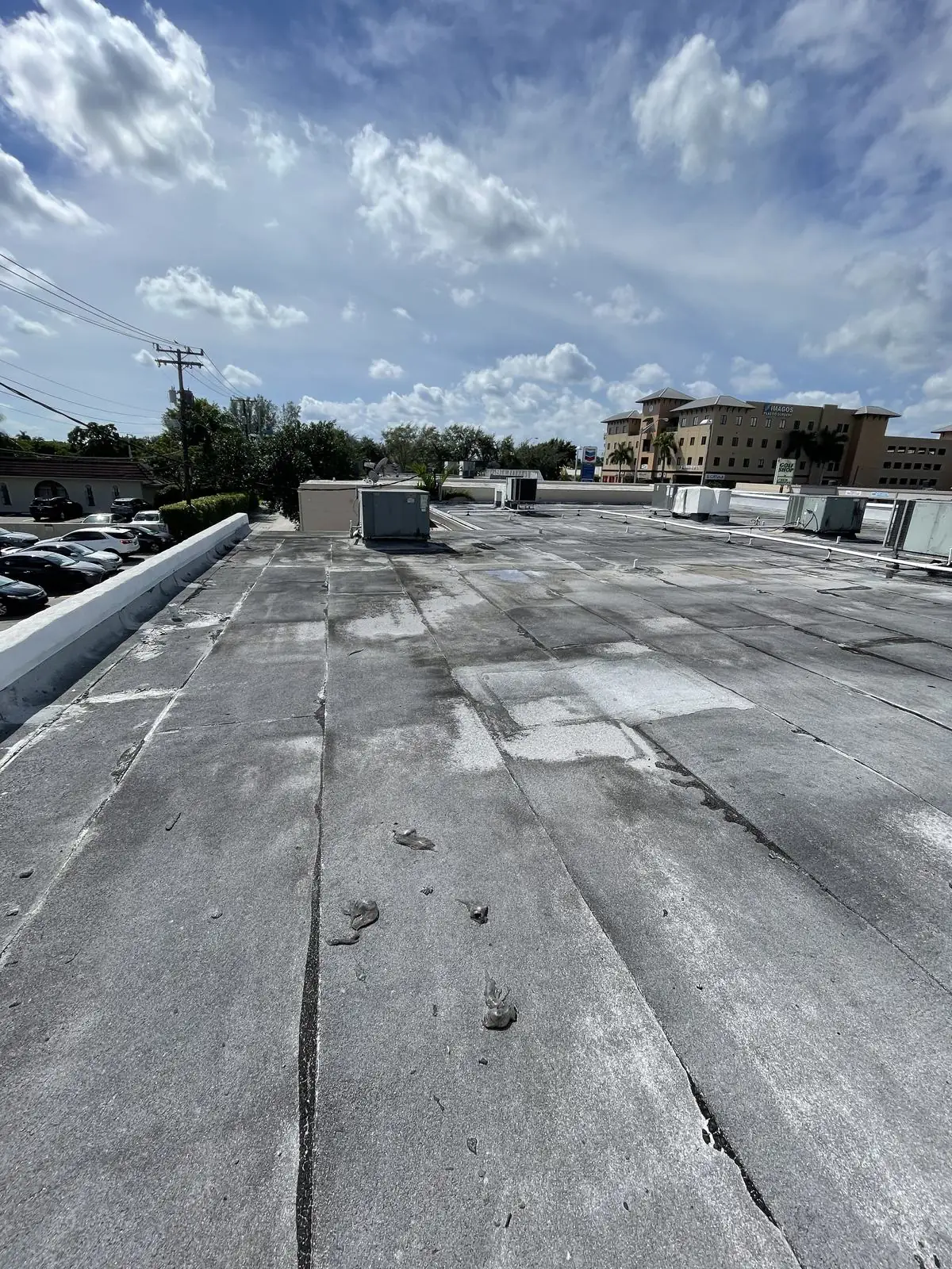 Low-slope flat roof with rooftop units on a building next to a parking lot, RTI Roofing job photo