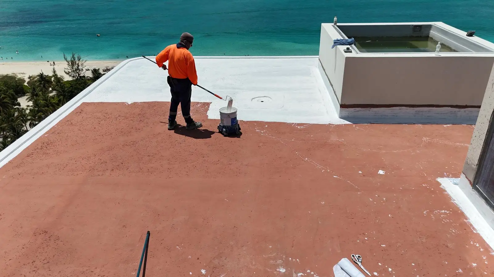 Installer rolling coating on the oceanfront rooftop, St. Regis, Turks and Caicos